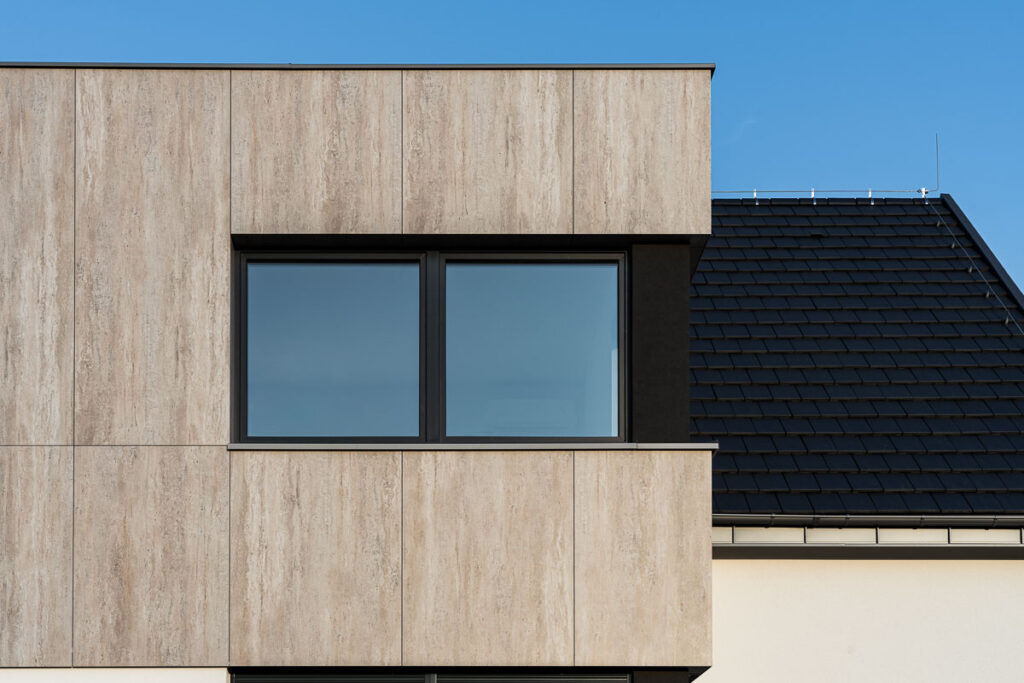 Nowoczesna elewacja domu jednorodzinnego z drewnianym wykończeniem i grafitowym dachem - Fotografia Architektury Wrocław