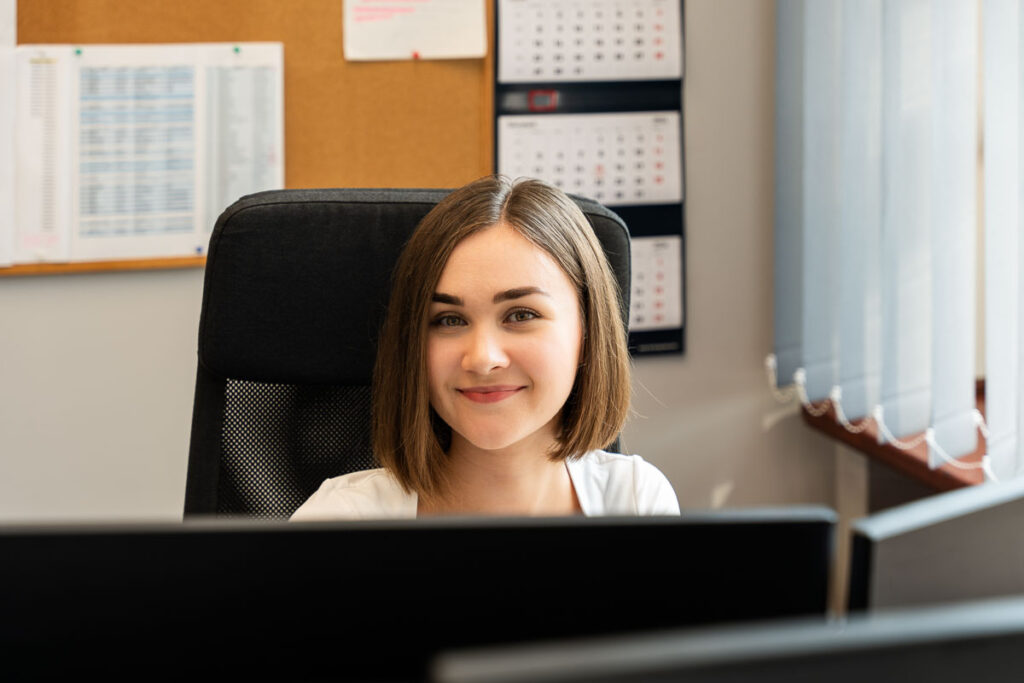 Uśmiechnięta kobieta pracująca przy komputerze w biurze - Fotografia Biznesowa Wrocław