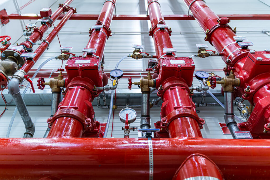 czerwone rury instalacji przeciwpożarowej z manometrami – fotografia przemysłowa Wrocław