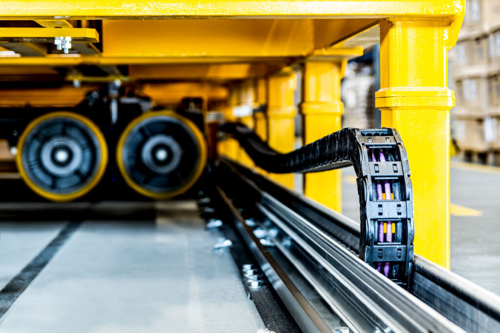 Prowadnica i łańcuch kablowy mobilnego regału magazynowego – detal techniczny w hali logistycznej, fotografia przemysłowa Wrocław