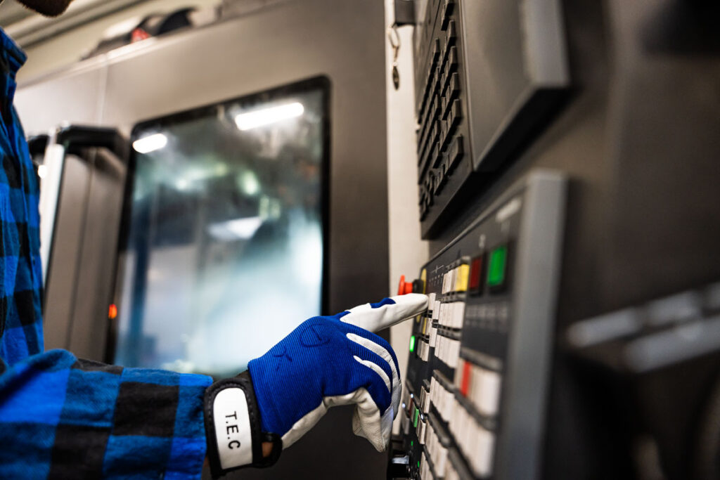 Operator w rękawicy obsługujący panel sterowania maszyny CNC – fotografia przemysłowa Wrocław