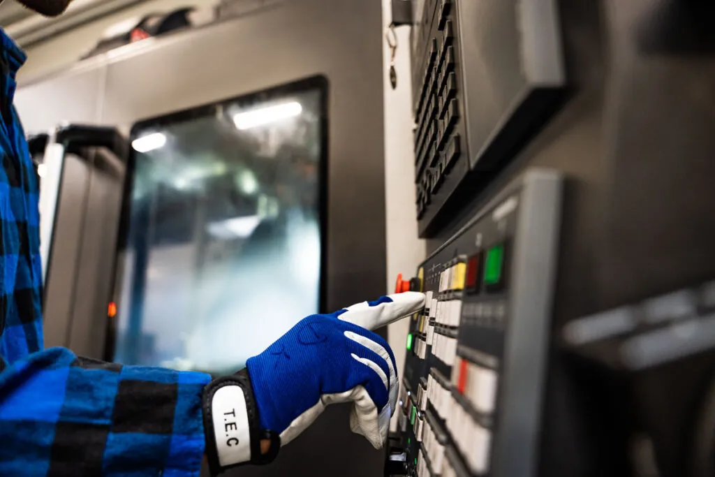 Operator w rękawicy obsługujący panel sterowania maszyny CNC – fotografia przemysłowa Wrocław