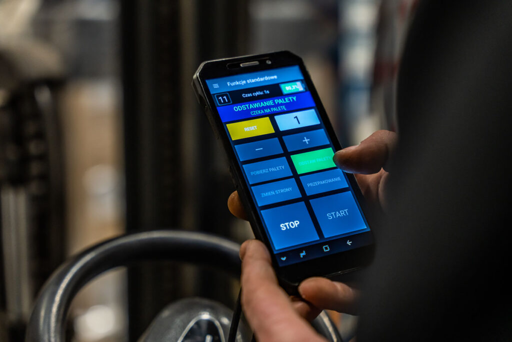 Operator wózka widłowego sterujący procesem logistycznym za pomocą aplikacji mobilnej – fotografia przemysłowa Wrocław