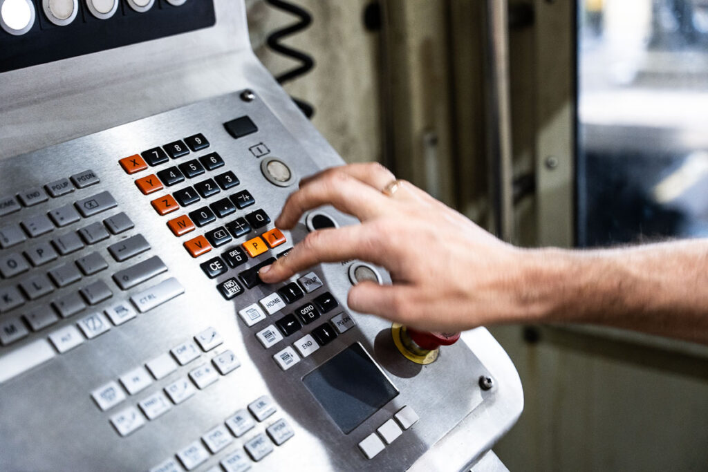 pulpit sterowniczy maszyny przemysłowej z ręką operatora – fotografia przemysłowa Wrocław