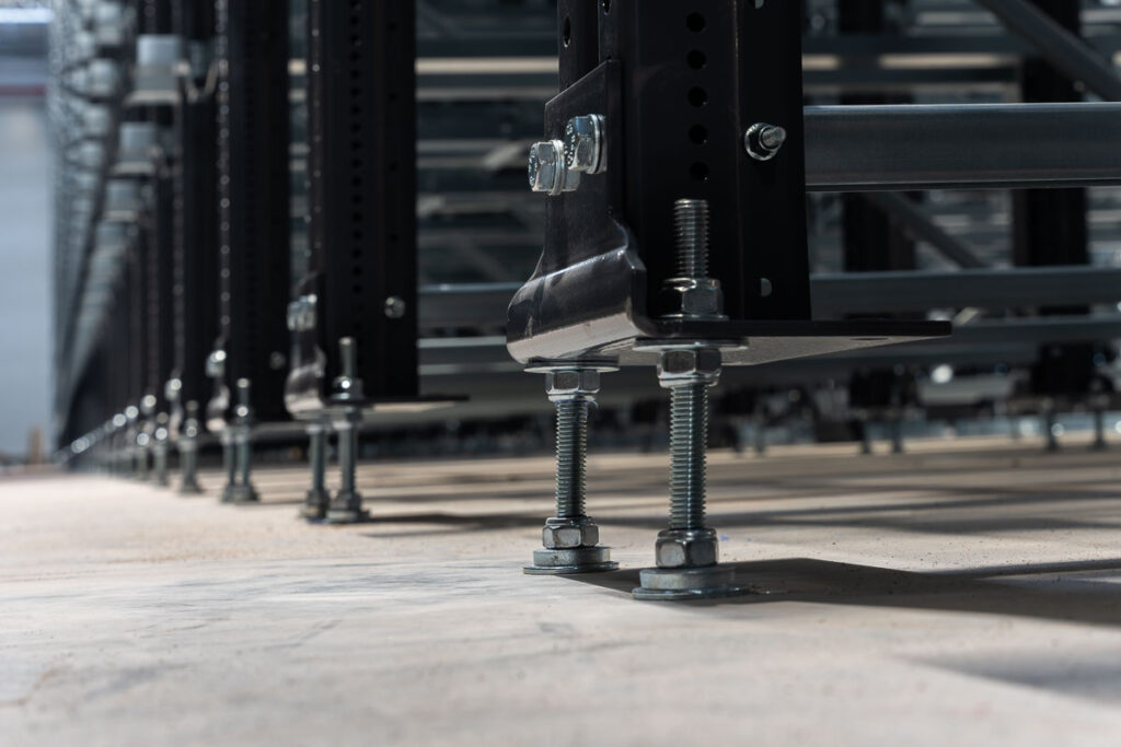Stalowe regały magazynowe zakotwione do posadzki z użyciem śrub regulacyjnych – fotografia przemysłowa Wrocław