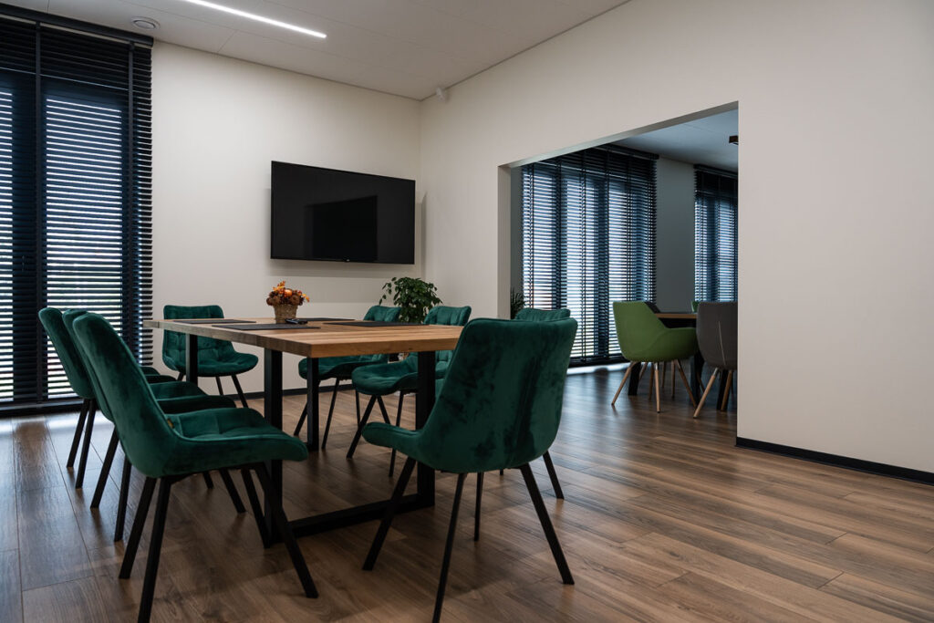 Sala konferencyjna z zielonymi krzesłami i stołem z drewnianym blatem - Fotografia Wnętrz Wrocław