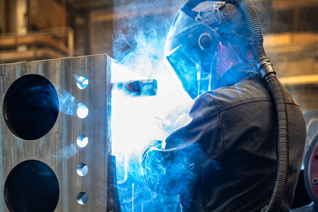 Spawacz w trakcie spawania w fabryce - fotografia przemysłowa Wrocław