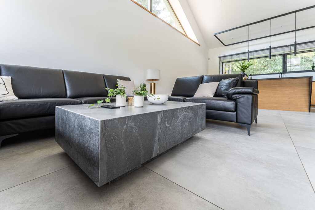 Stylowy stolik kawowy z kamienia w jasnym salonie z czarnymi skórzanymi sofami – Fotografia Wnętrz Wrocław