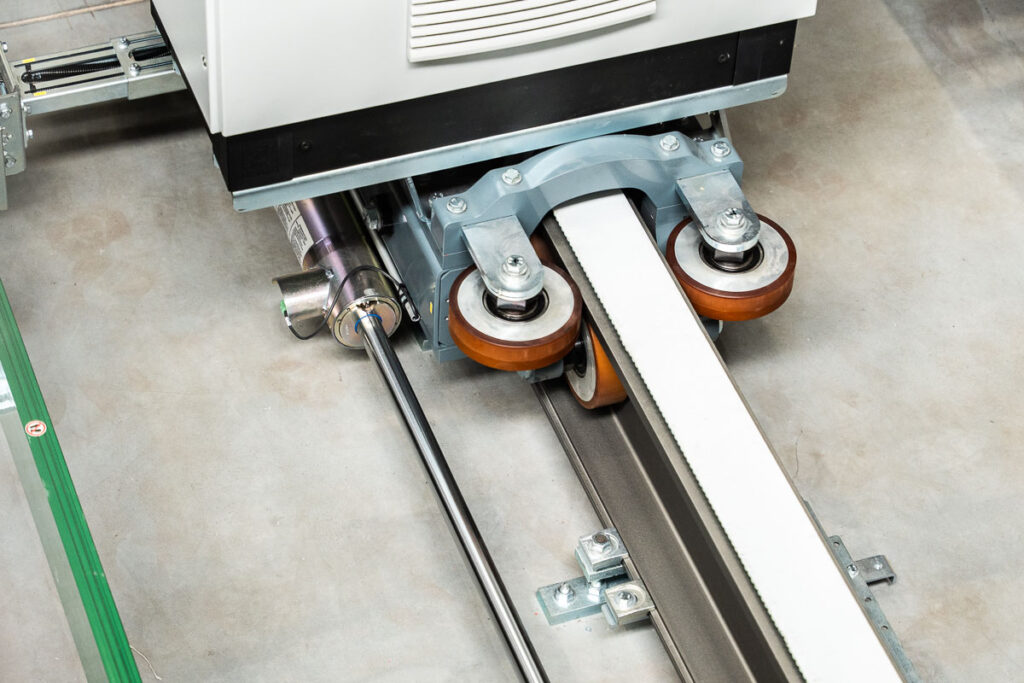 Zbliżenie na prowadzenie układnicy paletowej z kołami napędowymi i szyną jezdną – fotografia przemysłowa Wrocław