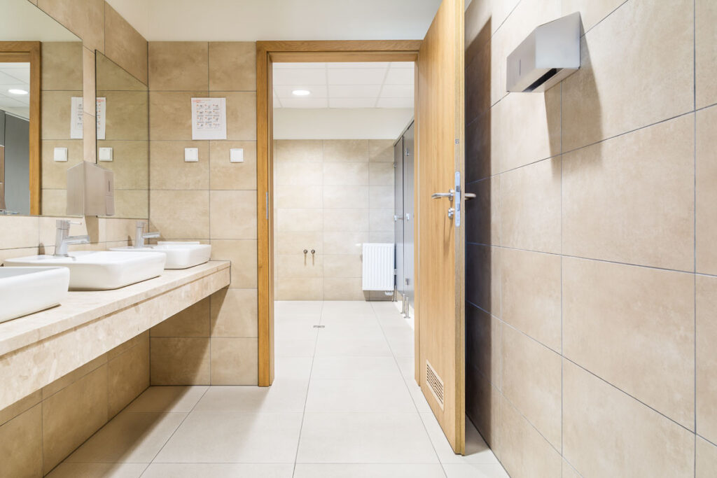 Nowoczesna toaleta publiczna z beżowymi płytkami i podwójnymi umywalkami – Fotografia Wnętrz Wrocław